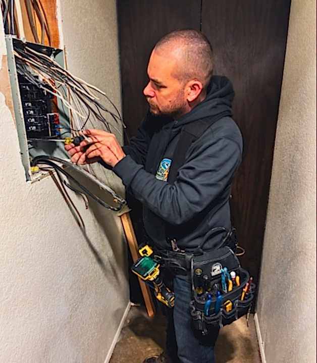 electrician-performing-electrical-repair-freeland Professional electrician troubleshooting an electrical issue in Freeland, Washington.