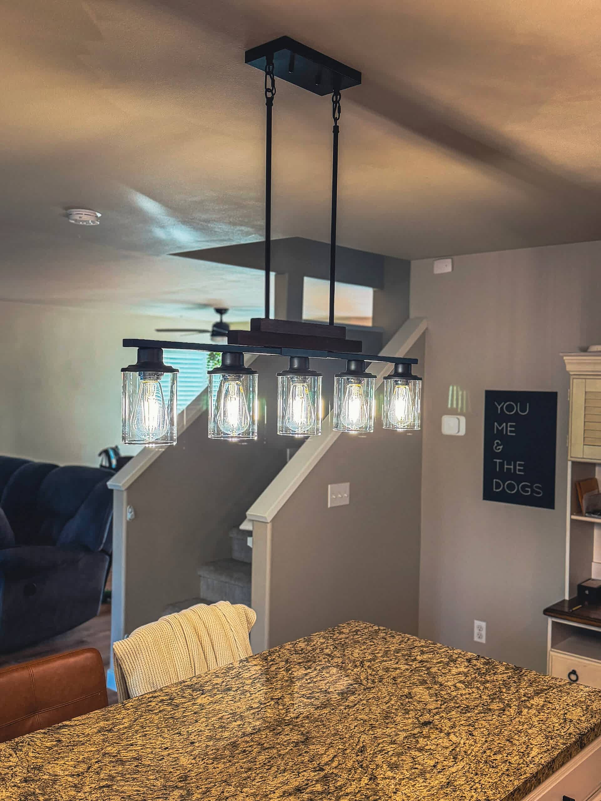 led-lighting-conversions-skagit-county-wa Modern kitchen island pendant light installation by Johnson Electrical Services featuring five clear glass LED fixtures above a granite countertop in a Skagit County, Washington home.