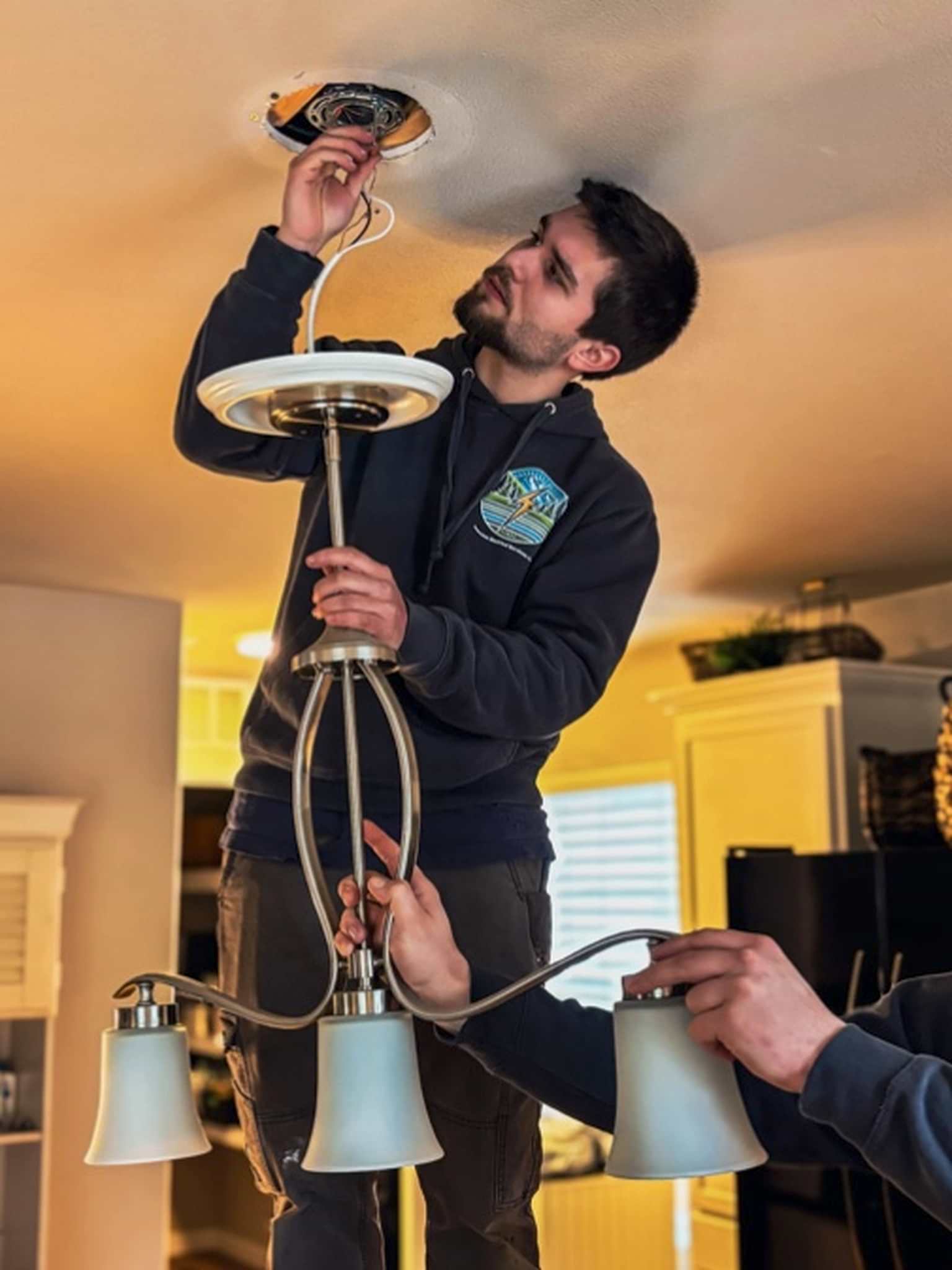 johnson-electrical-services-bellingham-wa-light-fixture-installation Johnson Electrical Services electrician installing a ceiling light fixture in a Bellingham, WA home.